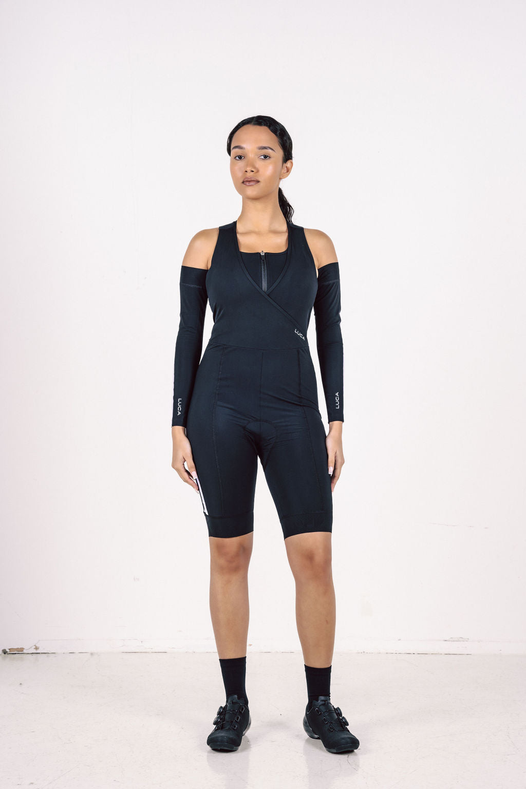 Model-standing-in-a-dark-navy-Road-All-In-One-women's-cycling- suit-with-detachable-cold-shoulder- sleeves