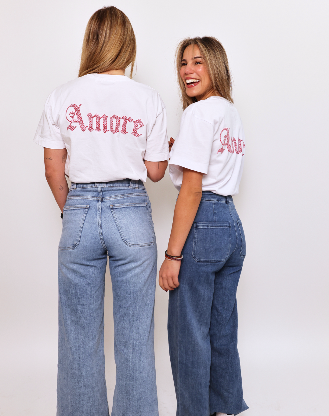 Close-up-showing-the-ornate-pink- "Amore"-back-print-on-a-white-t-shirt-worn-with-denim