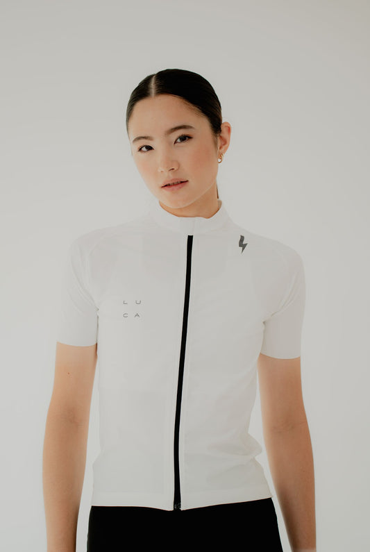 Front-view-close-up-of-a-female-model-wearing-a-white-short-sleeve-cycling-jersey-with-a-black-full-length-zipper-Features-include-the-small-black-LUCA-logo-on-the-chest-and-a-lighting-bolt-grapic-on-the-shoulder