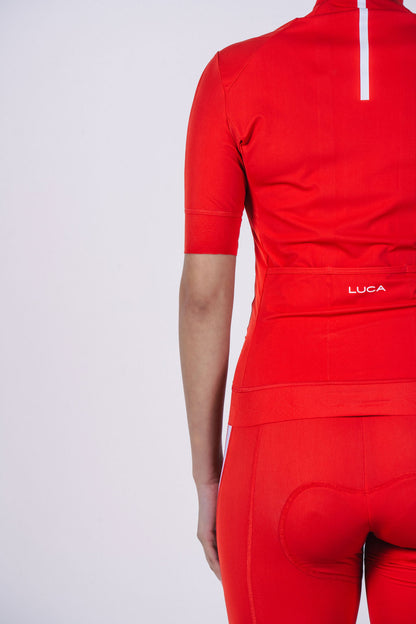 Close-up-showing-the-back-pocket- of-a-red-cycling-jersey-with-the- LUCA-logo-and-a-white-reflective- strip