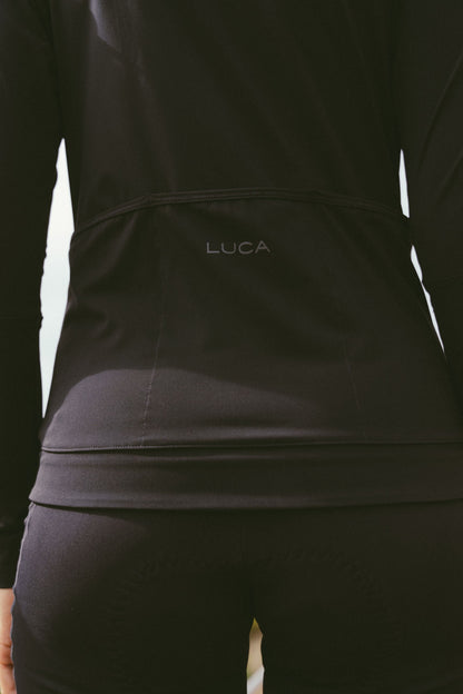 Close-up-of-the-lower-back-of-the-black-Horizon-jersey-showing-the-subtle-LUCA-branding-positioned-above-the-stitched-seam-of-the-three-reinforced-rear-storage-pockets