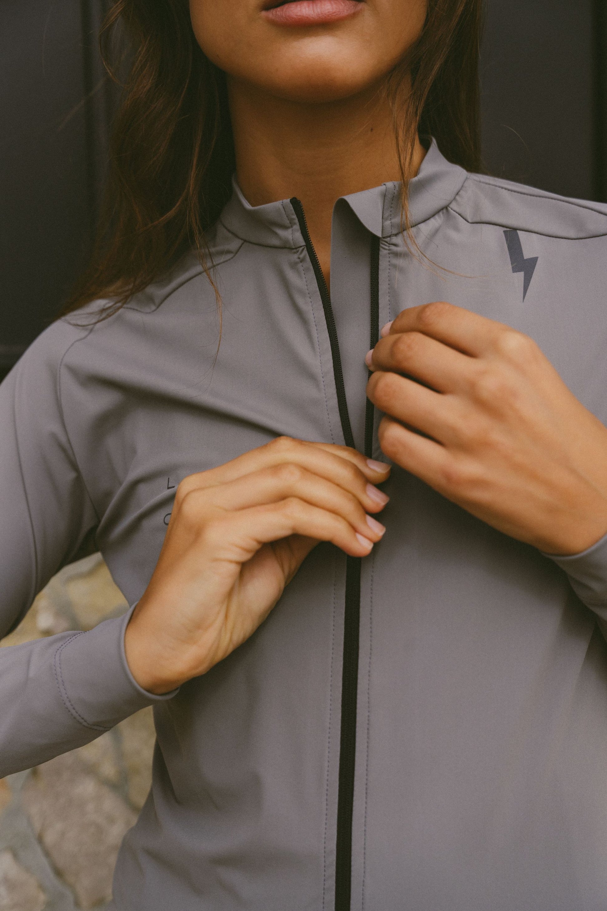 Close-up-of-a-person-zipping-u-the-full-length-front-zipper-of-the-gray-Horizon-long-sleeve-athletic-jersey-highlighting-the-high-collar-and-quality-tailoring