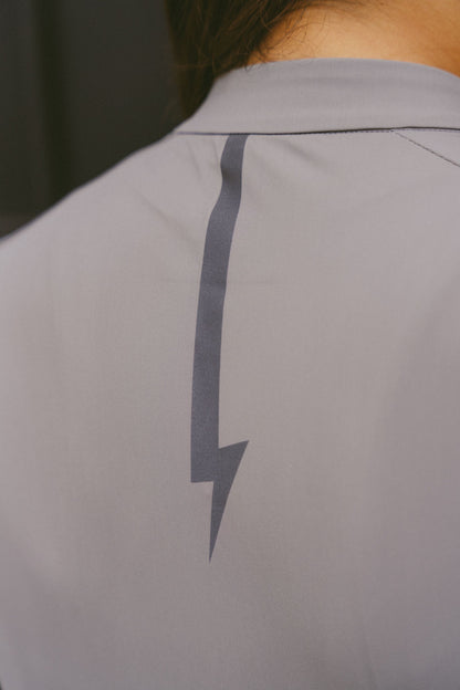 Close-up-of-the-reflective-lighting-bolt-on-the-upper-back-of-the-gray-Harizon-long-sleeve-athletic-jersey-designed-for-enhanced-visibility-and-signature-branding