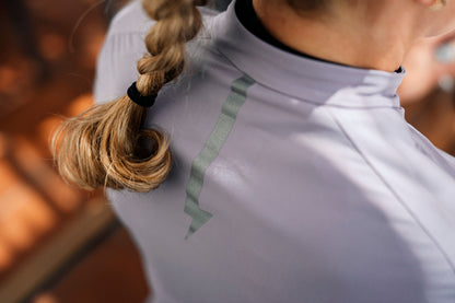Close-up-of-the-light-graylilac-athletic-jersey-high-neck-collar-and-raglan-shoulder--seams-A-person-with-blond-braided-hair-is-wearing-the-shirt