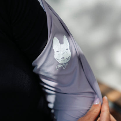 Close-up-of-a-purple-sleeveless-athletic-top-with-a-white-dog-illustration-and-fun-dog-text-graphic-held-against-a-blurred-background