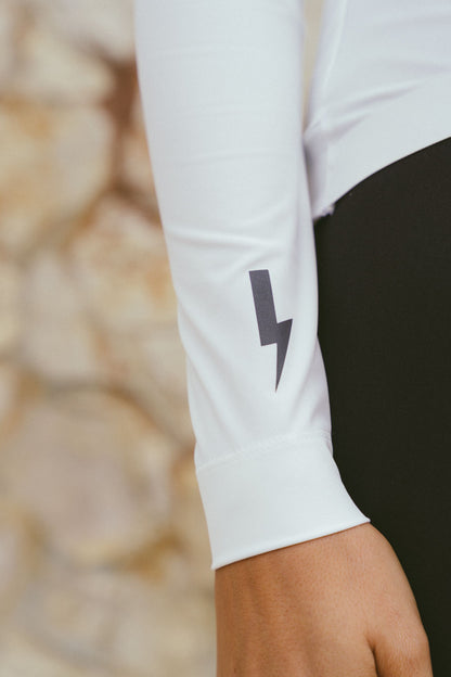 Close-up-detail-of-the-sleeve-cuff-on-the-white-long-sleeve-cycling-jersey-showing-the-dark-grey-lighting-bolt-sign-on-the-forearm-and-the-clean-tailored-wrist-band