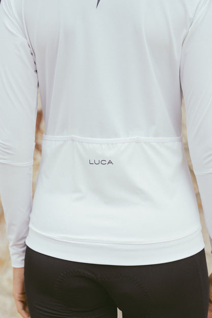 Close-up-of-the-lower-back-of-the-white-Luca-long-sleeve-cycling-jersey-clearly-showing-the-elasticated-rear-pocket-line-the-subtle-LUCA-branding-prited-above-the-gripped-hem-to-keep-the-jersey-in-place-during-a-ride