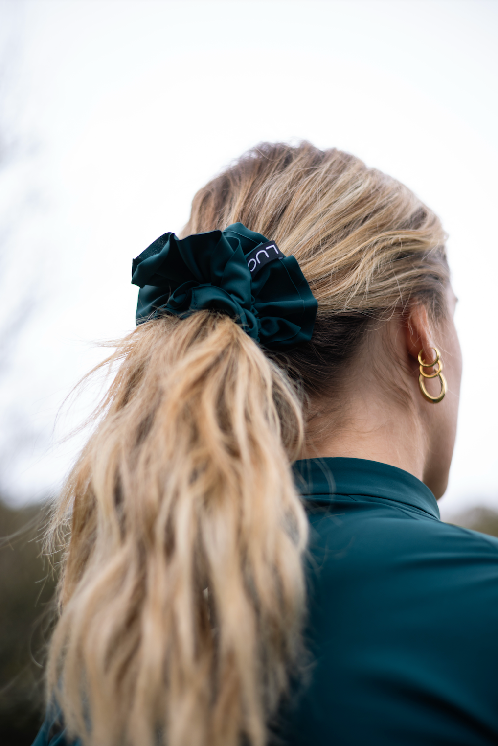 Close-up-of-a-Uplift-Scrunchie-Teal-
with-a-dark-green-Luca-logo- scrunchie