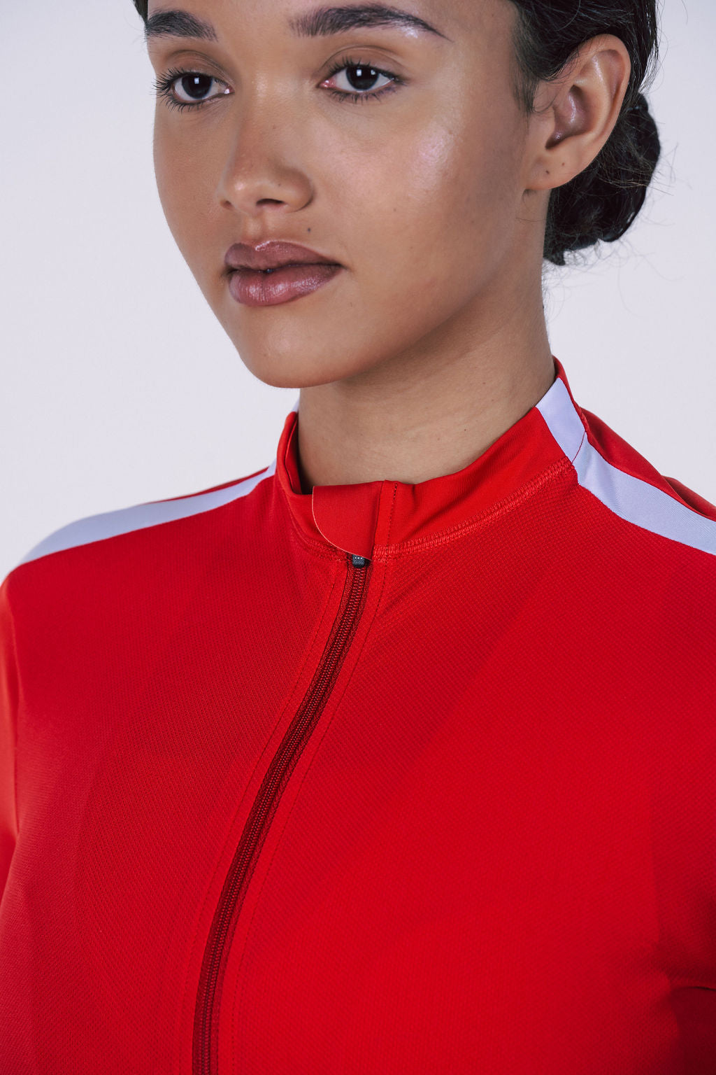 Detail-of-a-red-cycling-top-with-a-high-collar-zipper-and-silver- reflective-stripe-across-the-shoulder