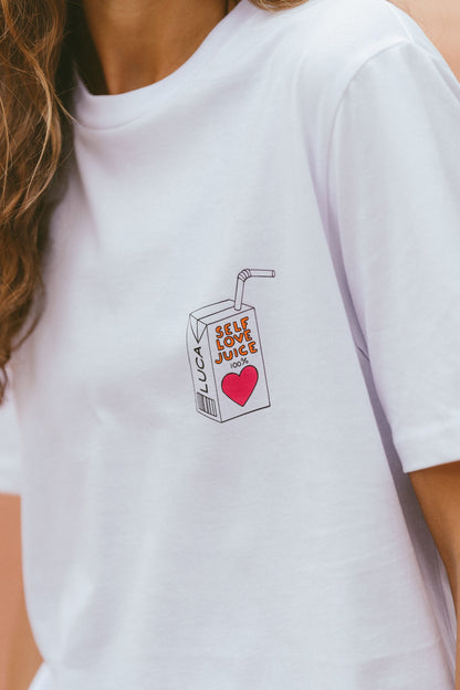 A-close-up-studio-shot-of-a-white-cotton-crew-neck-t-shirt-with-a-cetered-chest-graphic-The-detailed-graphic-depicts-a-retro-style-juice-box-with-a-straw-featuring-the-text-SELF-LOVE-JUICE-and-a-large-red--heart-The-brand-name-LUCA-is-printed-vertically-on-the-side-of-the-box-